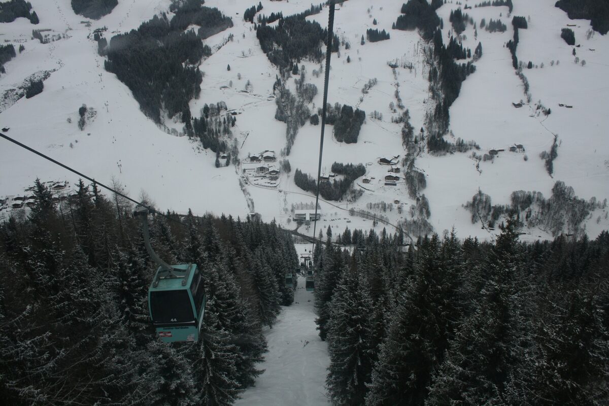 A Nordbahn gondola cabin climbing over snowy forest and pistes on the Zwölferkogel side above Hinterglemm