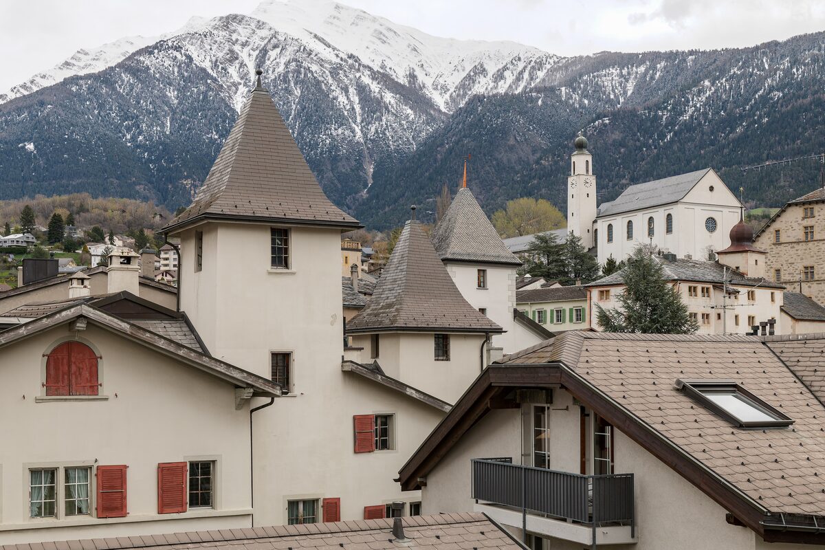 The old town of Brig with its church and rooftops, below snow-dusted peaks