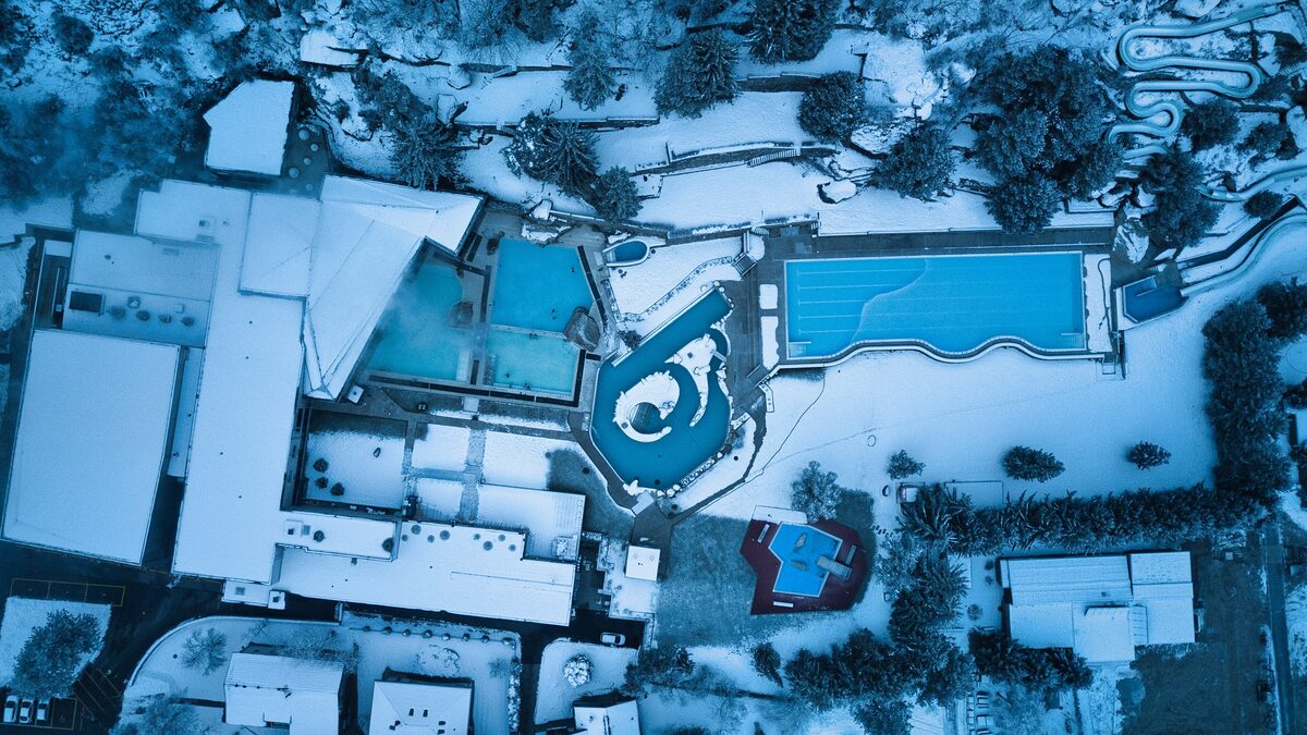 Aerial view of the snow-covered Brigerbad thermal baths with its outdoor pools and paths