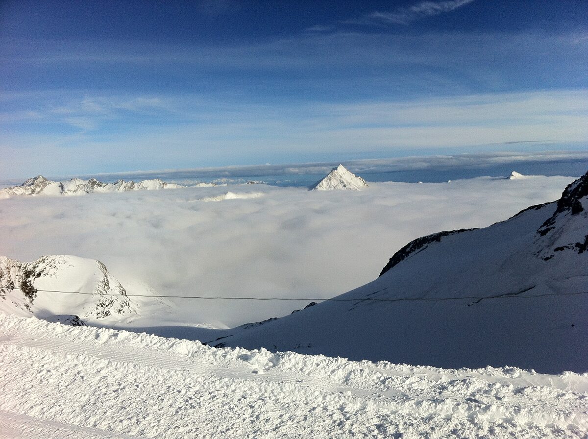 View from a ski piste on the Mittelallalin over a sea of cloud to a distant snowy peak