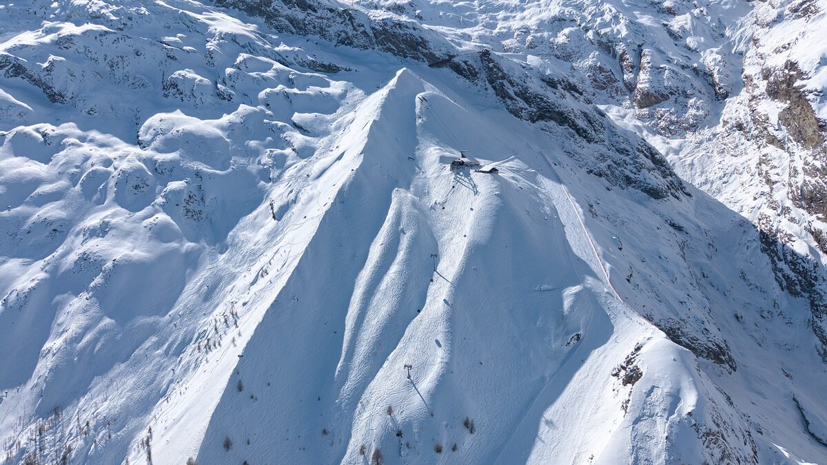 A steep snow ridge with a ski piste running along its crest