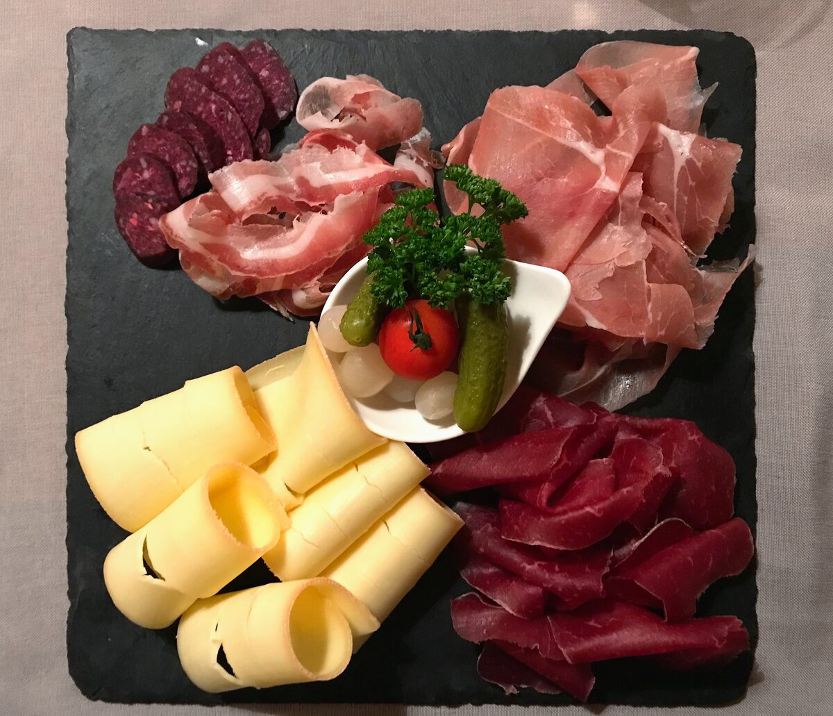 A slate platter with Valais dried beef, cured ham and cheese