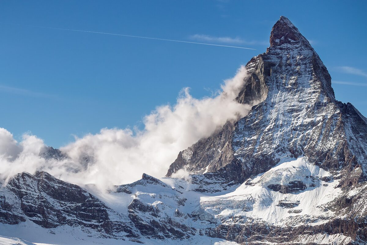 The Matterhorn with snow on its flanks and a bank of cloud against a blue sky