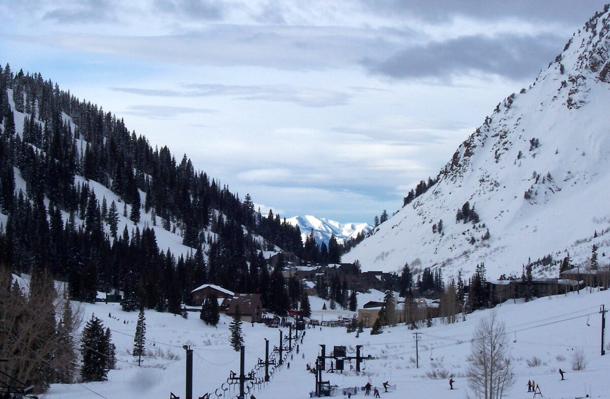 Snow-covered Little Cottonwood Canyon at Alta, with lift lines and lodge roofs at the foot of steep, forested slopes