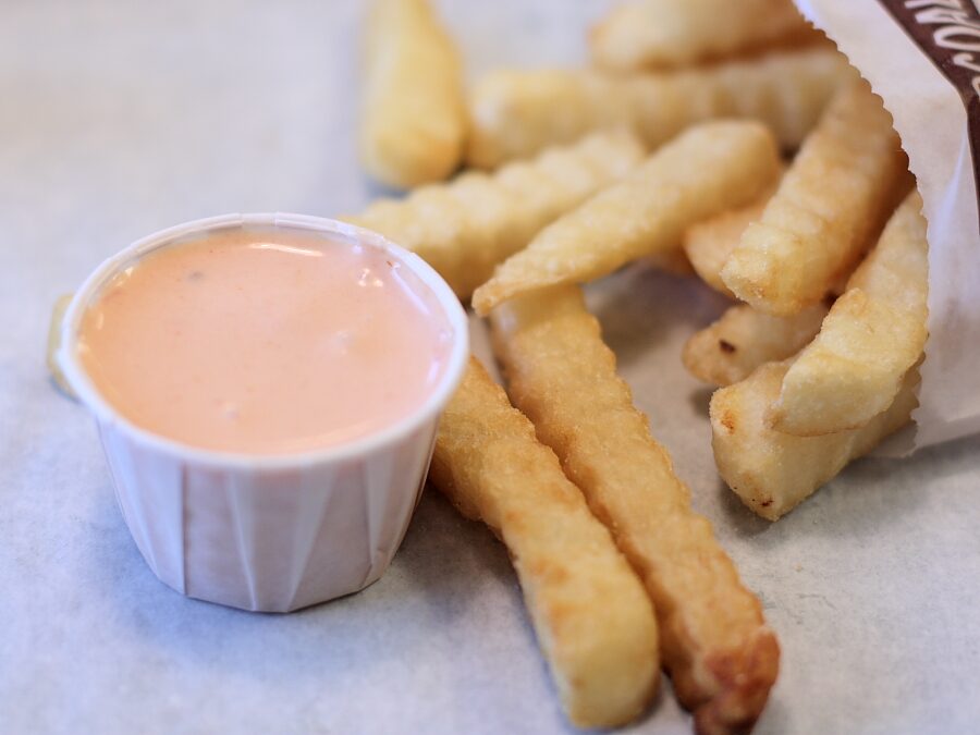 A paper cup of pink fry sauce beside a pile of french fries