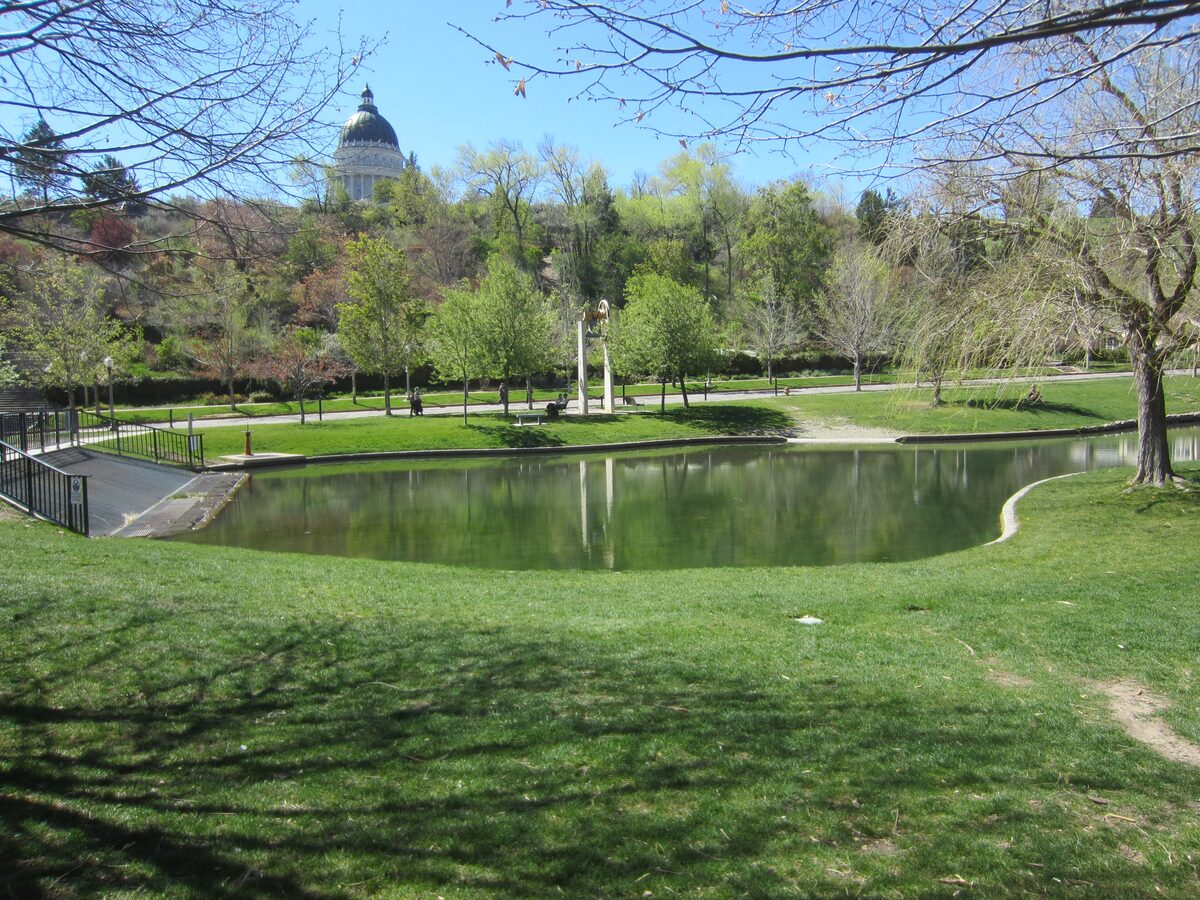 The pond and lawns of Memory Grove below the hillside, with the Capitol dome showing through the trees