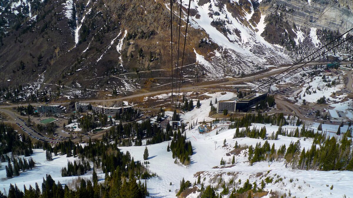 Snowbird's village and the canyon road seen from above, with snow patches on the steep slopes around it