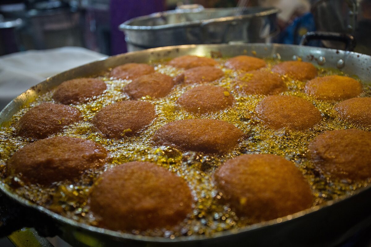 Acarajé balls frying in a wide pan of dendê oil, in a photo labeled Acarajé da Cira