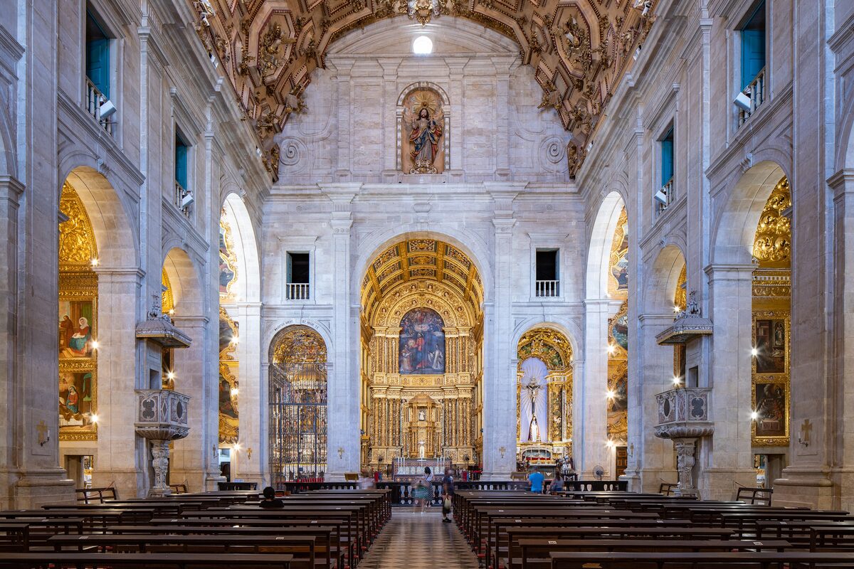 Inside the Cathedral Basilica of Salvador: a white nave with rows of pews and gilded altarpieces at the far end