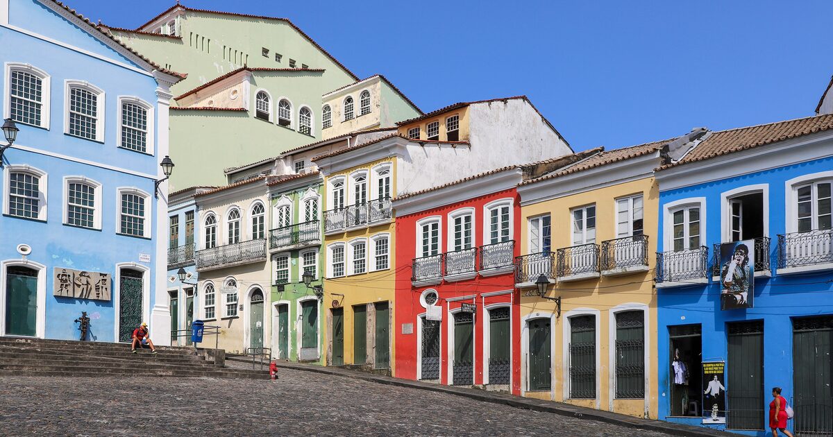 Colorful colonial houses in blue, yellow, red and green along a cobbled street in Pelourinho under a bright blue sky