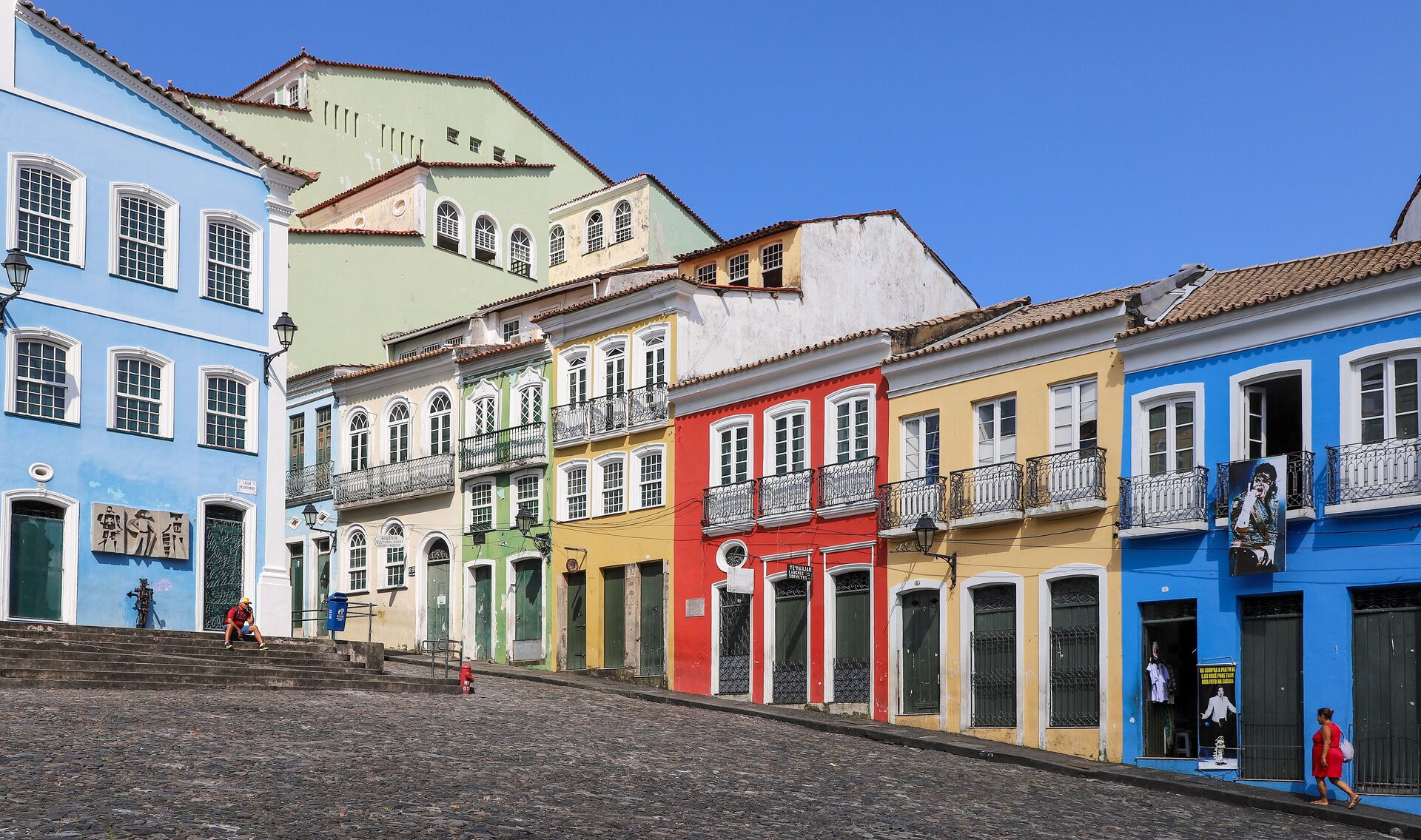 Colorful colonial houses in blue, yellow, red and green along a cobbled street in Pelourinho under a bright blue sky