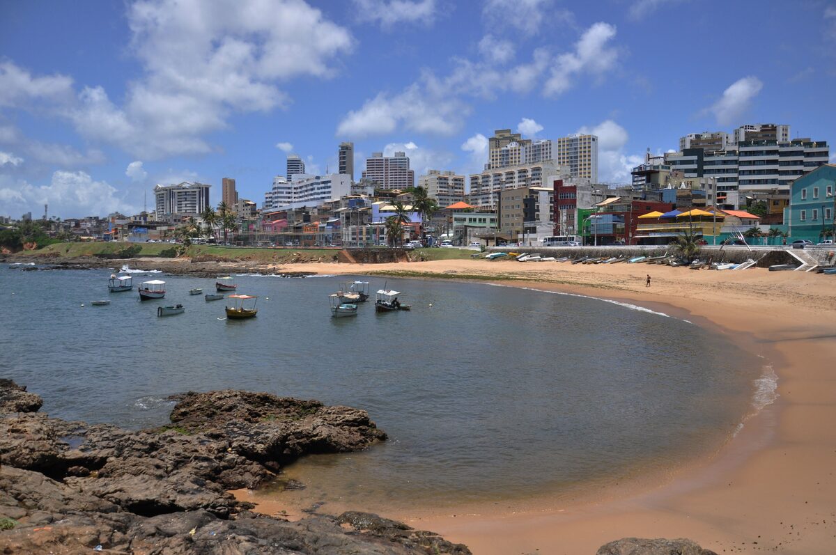 The curved Rio Vermelho beach with fishing boats in the calm cove and the neighborhood's colorful buildings behind