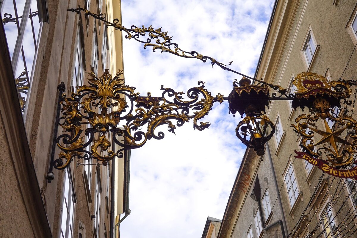 Gilded wrought-iron guild signs hanging over the narrow Getreidegasse in Salzburg