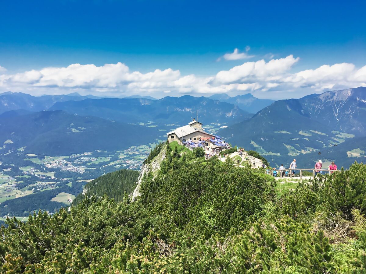 The stone Kehlsteinhaus on its rocky ridge above the Berchtesgaden valley, with visitors on the path