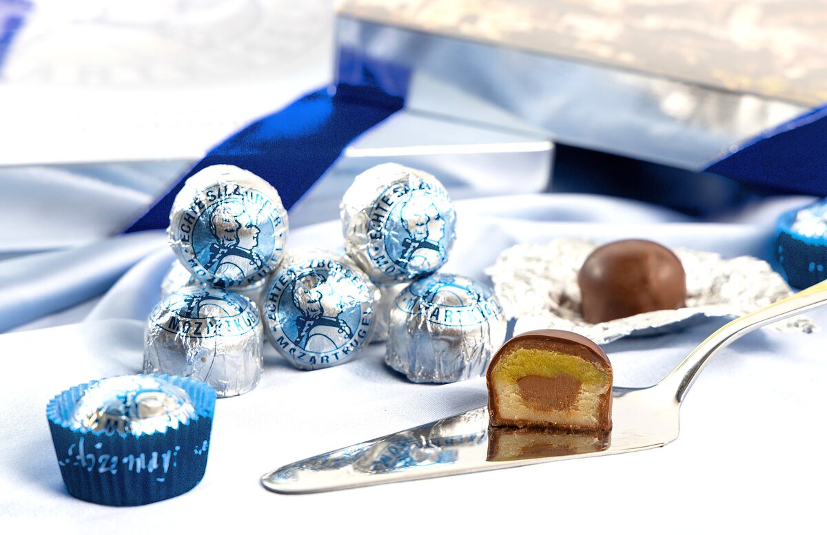 Mozartkugeln in silver and blue foil, one cut open to show the marzipan and nougat inside
