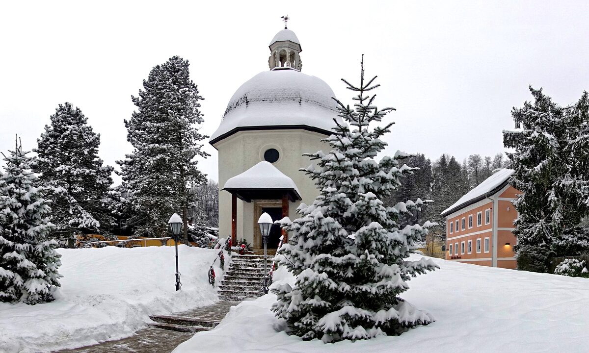 The small round Silent Night Chapel in Oberndorf among snowy fir trees
