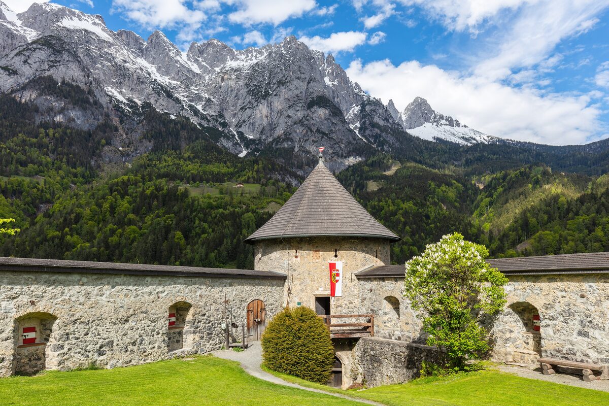 The walls and round tower of Hohenwerfen Castle, with the jagged peaks of the Tennengebirge behind