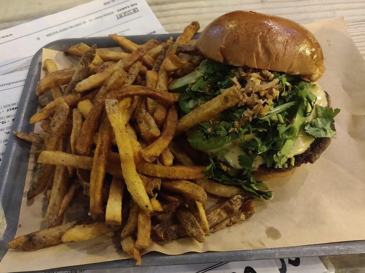 A cheeseburger with a tray of seasoned fries