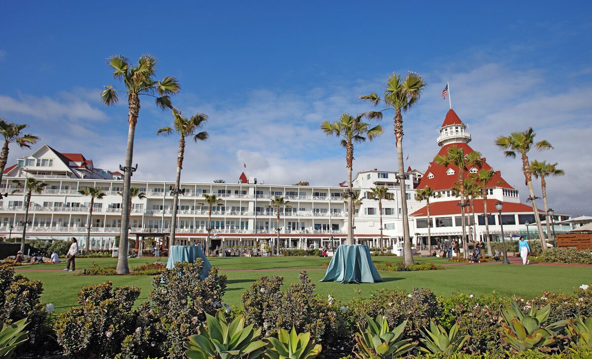 The Hotel del Coronado's red-roofed turret above palms and a green lawn