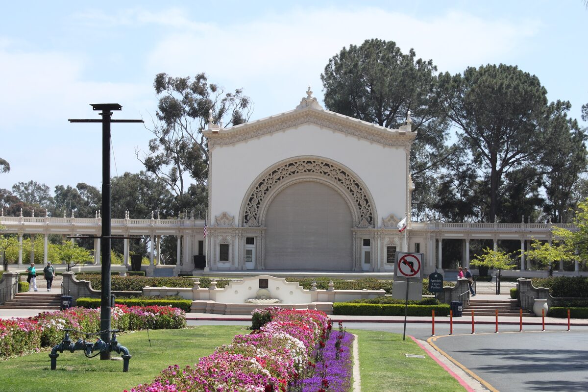 The white arched Spreckels Organ Pavilion behind a bed of pink flowers