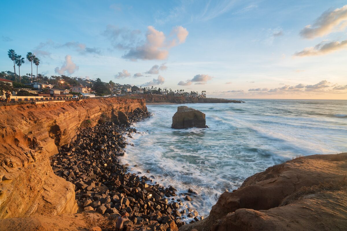 Golden sandstone cliffs and surf at Sunset Cliffs under a pastel sky