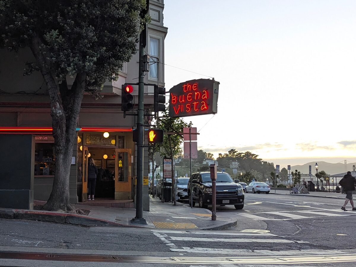 The corner entrance and red neon sign of the Buena Vista Cafe at the foot of Russian Hill