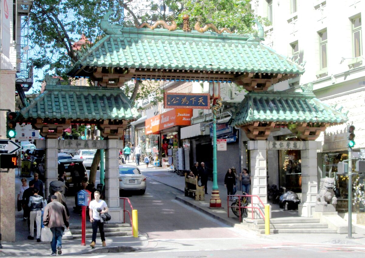 The green-tiled Dragon Gate at the Bush Street entrance to Chinatown, with shoppers walking through