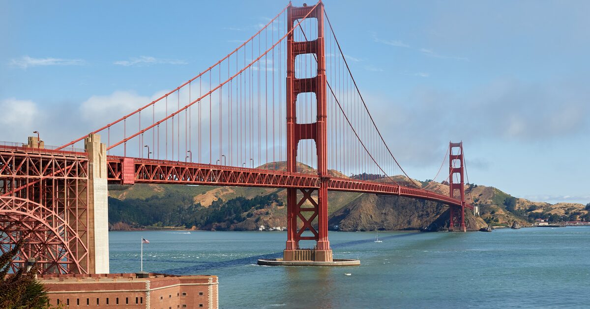 The Golden Gate Bridge on a clear day, its red towers and cables seen from the Fort Point side with the Marin Headlands behind
