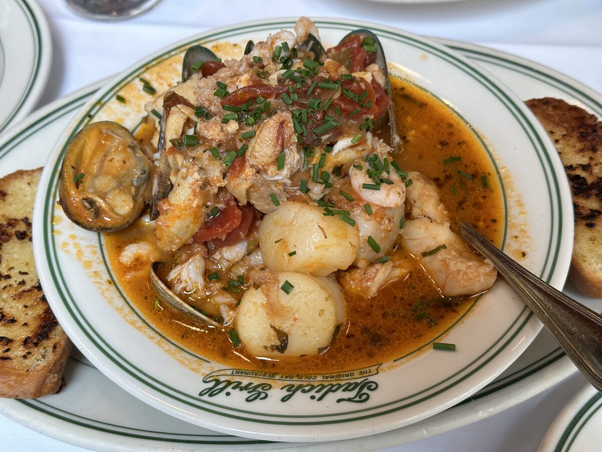 A plate of cioppino with clams, scallops, fish and tomato broth, served with toast at Tadich Grill