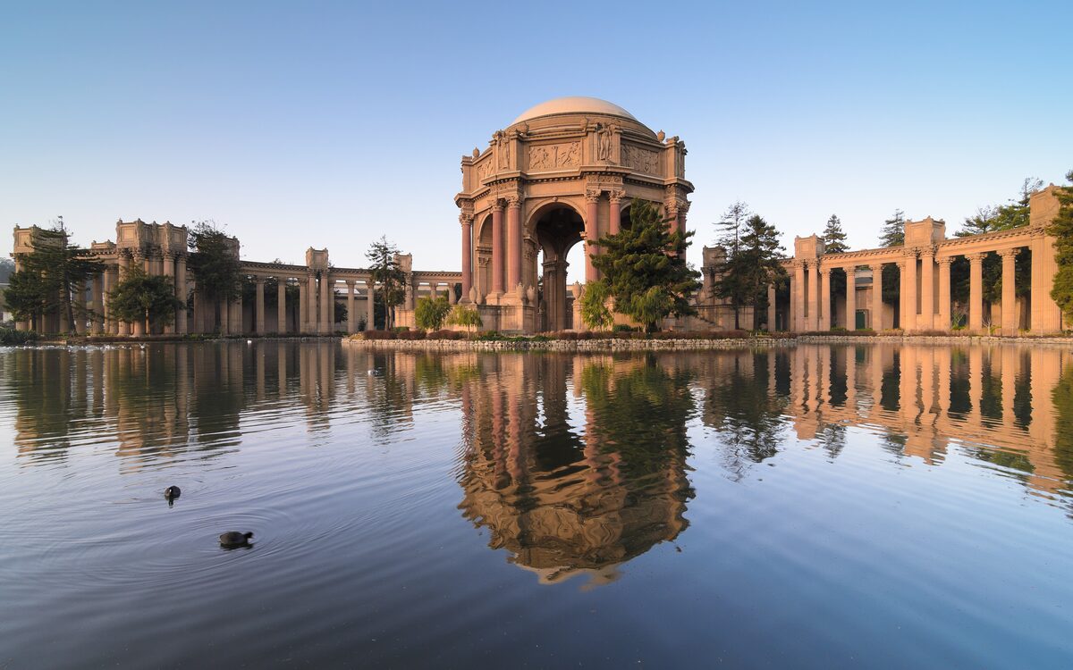 The domed rotunda and colonnade of the Palace of Fine Arts reflected in its lagoon on a clear morning
