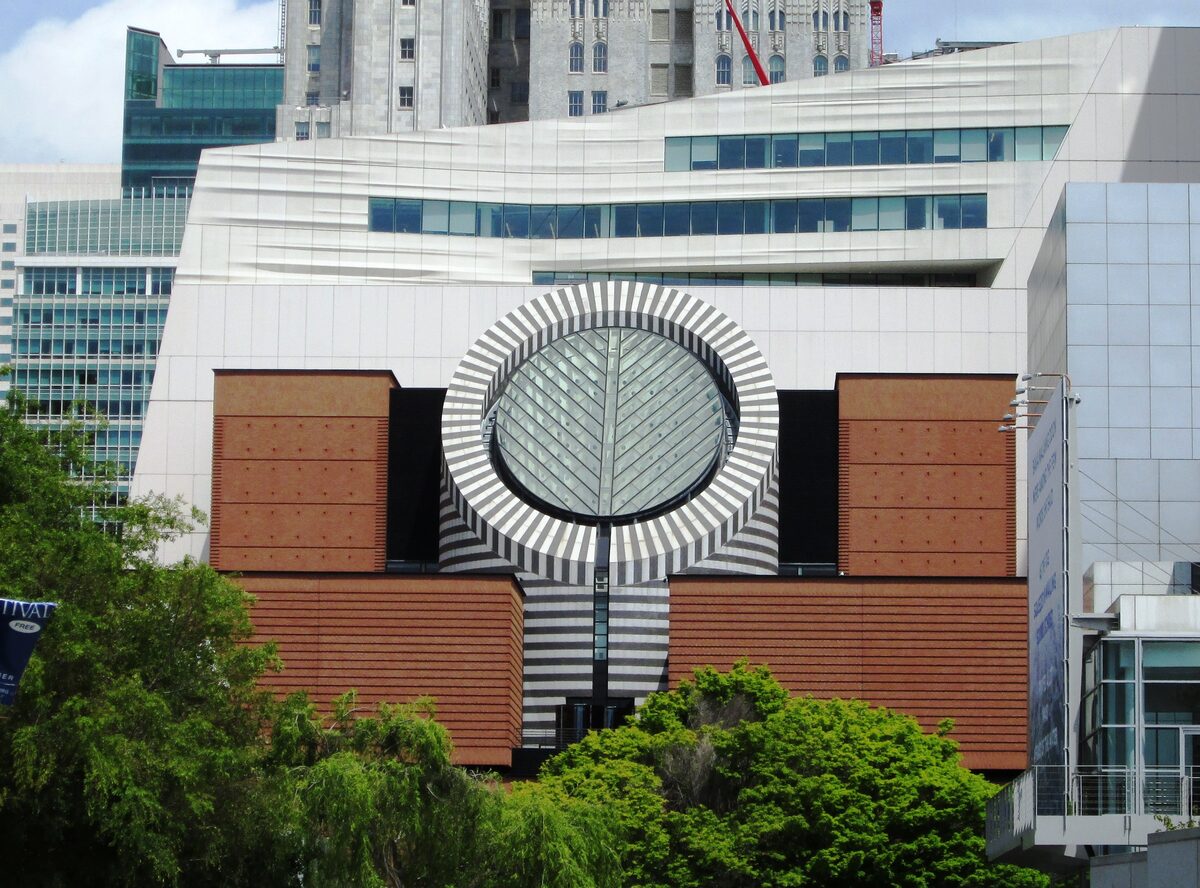 The striped round skylight and brick-red facade of SFMOMA seen from Yerba Buena Gardens