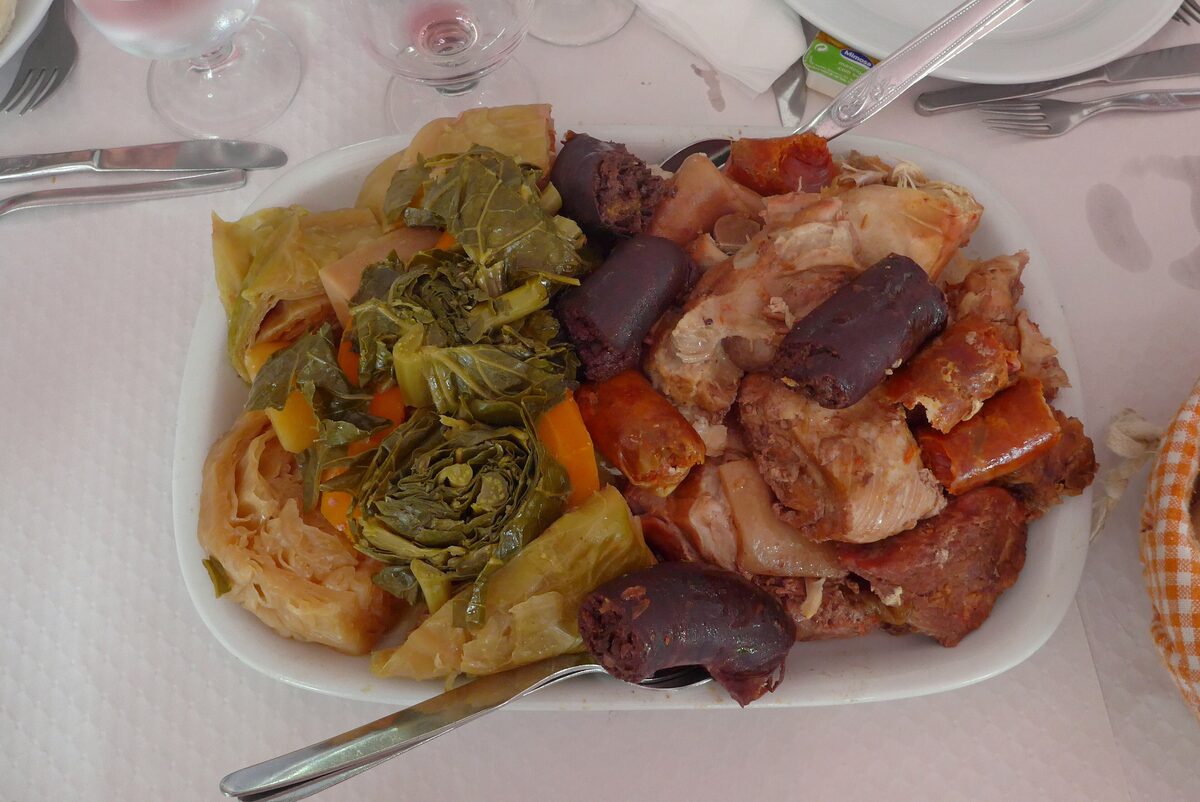 A plate of cozido with cabbage, potatoes, carrots and several kinds of sausage and meat