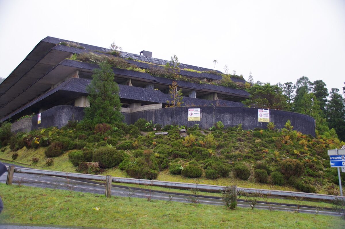 The concrete hull of the abandoned Monte Palace hotel above the Sete Cidades road, its roof planted with grass