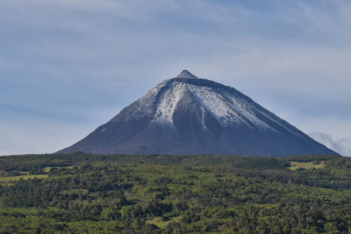 The cone of Pico volcano rising above green lowlands and forest