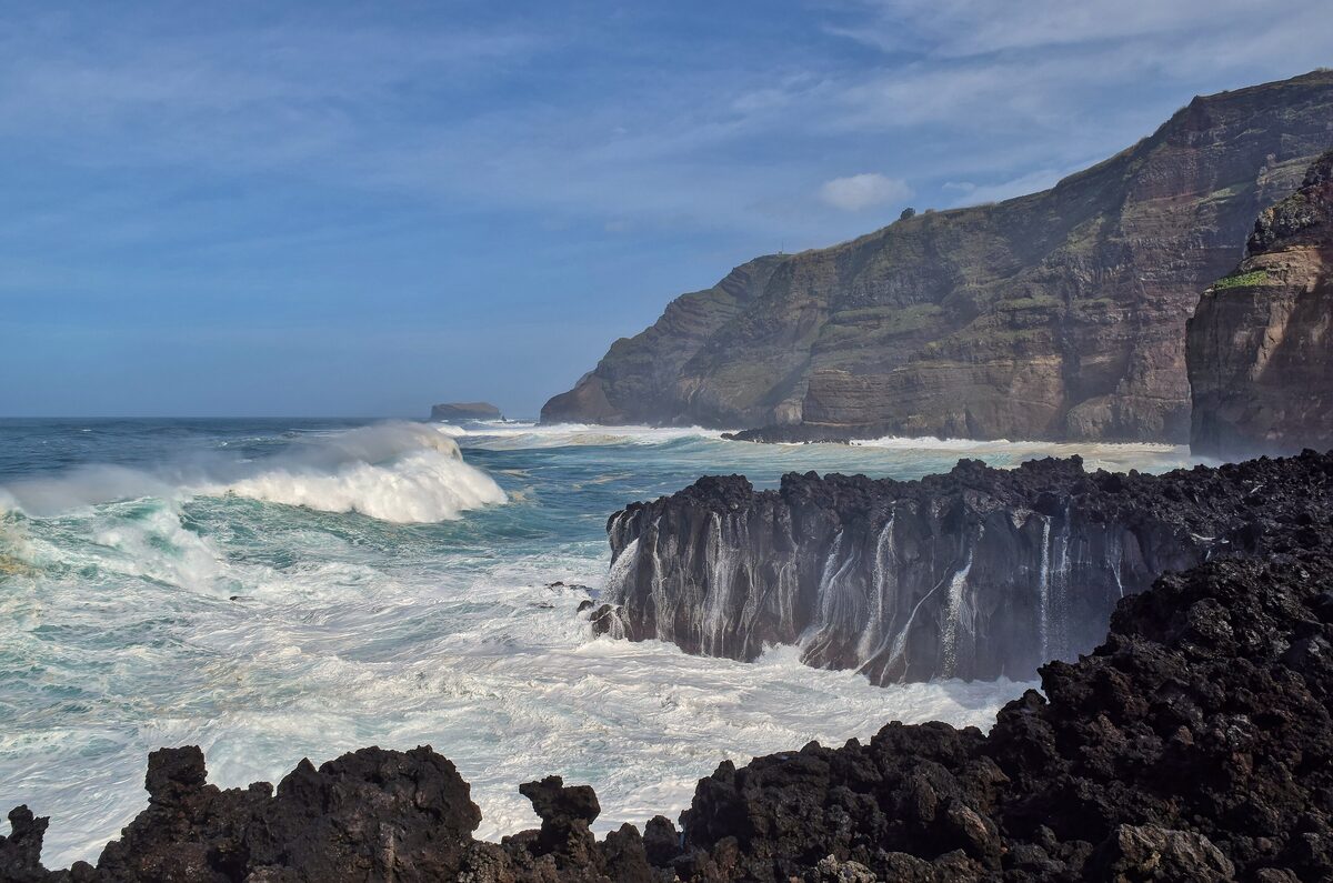 Waves breaking against black lava cliffs at Ponta da Ferraria on the west coast