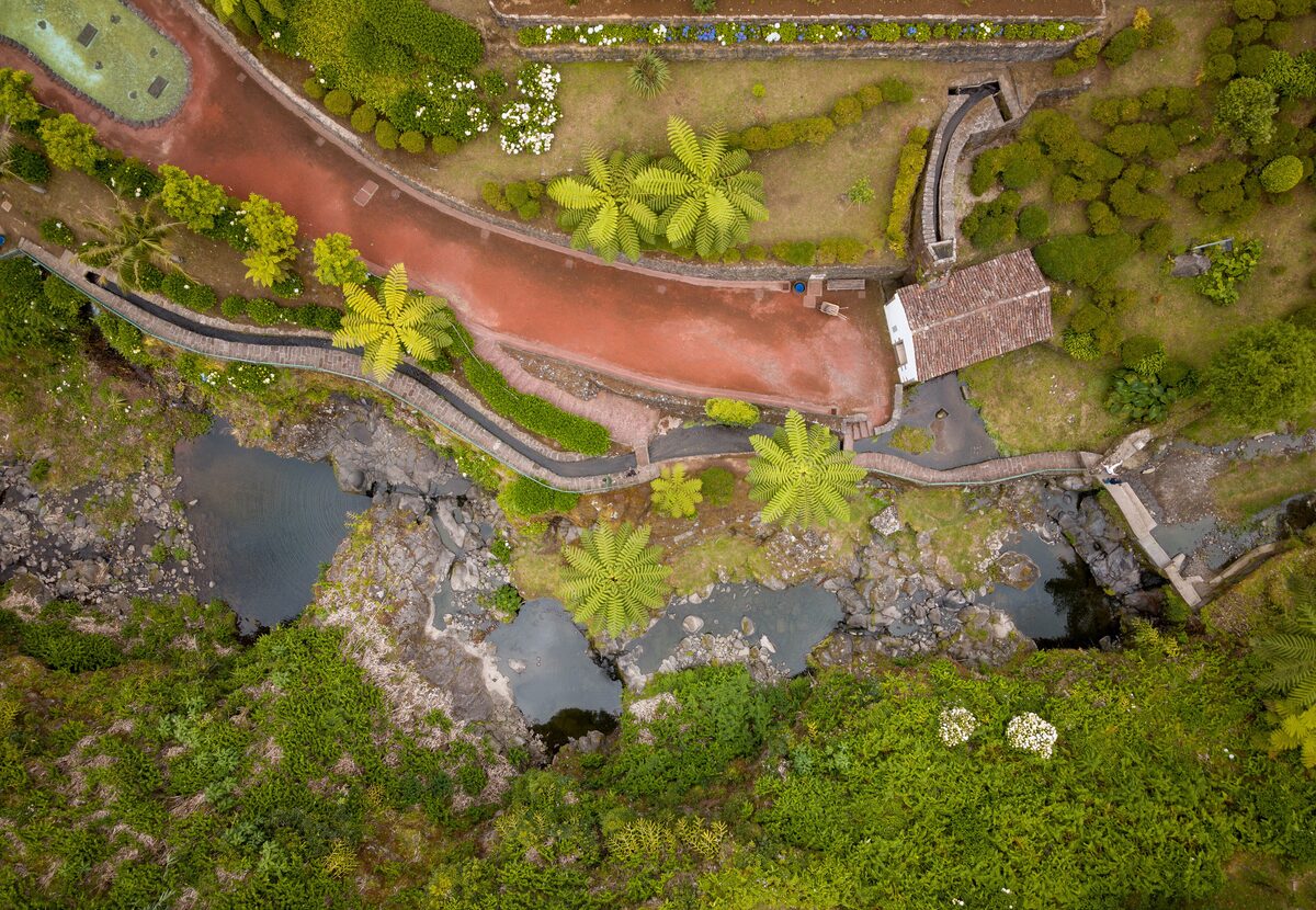 Aerial view of the Ribeira dos Caldeirões park with a red path, small dark pools and tree ferns