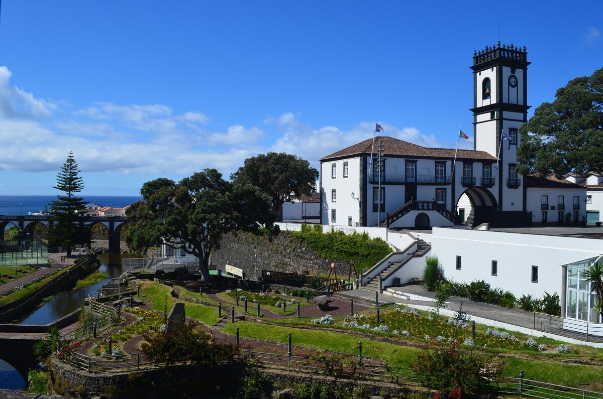 The white town hall of Ribeira Grande with its clock tower, above a terraced garden and the stream