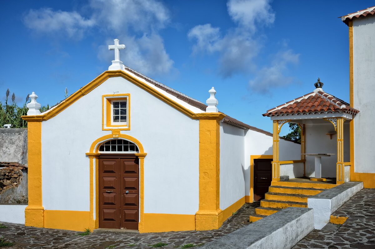 A whitewashed chapel with yellow trim and a red-tiled porch on Santa Maria
