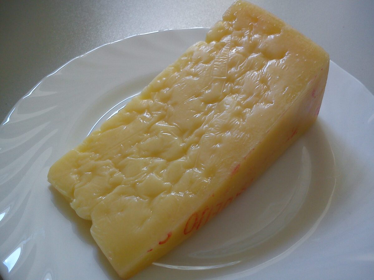 A wedge of pale yellow São Jorge cheese on a white plate