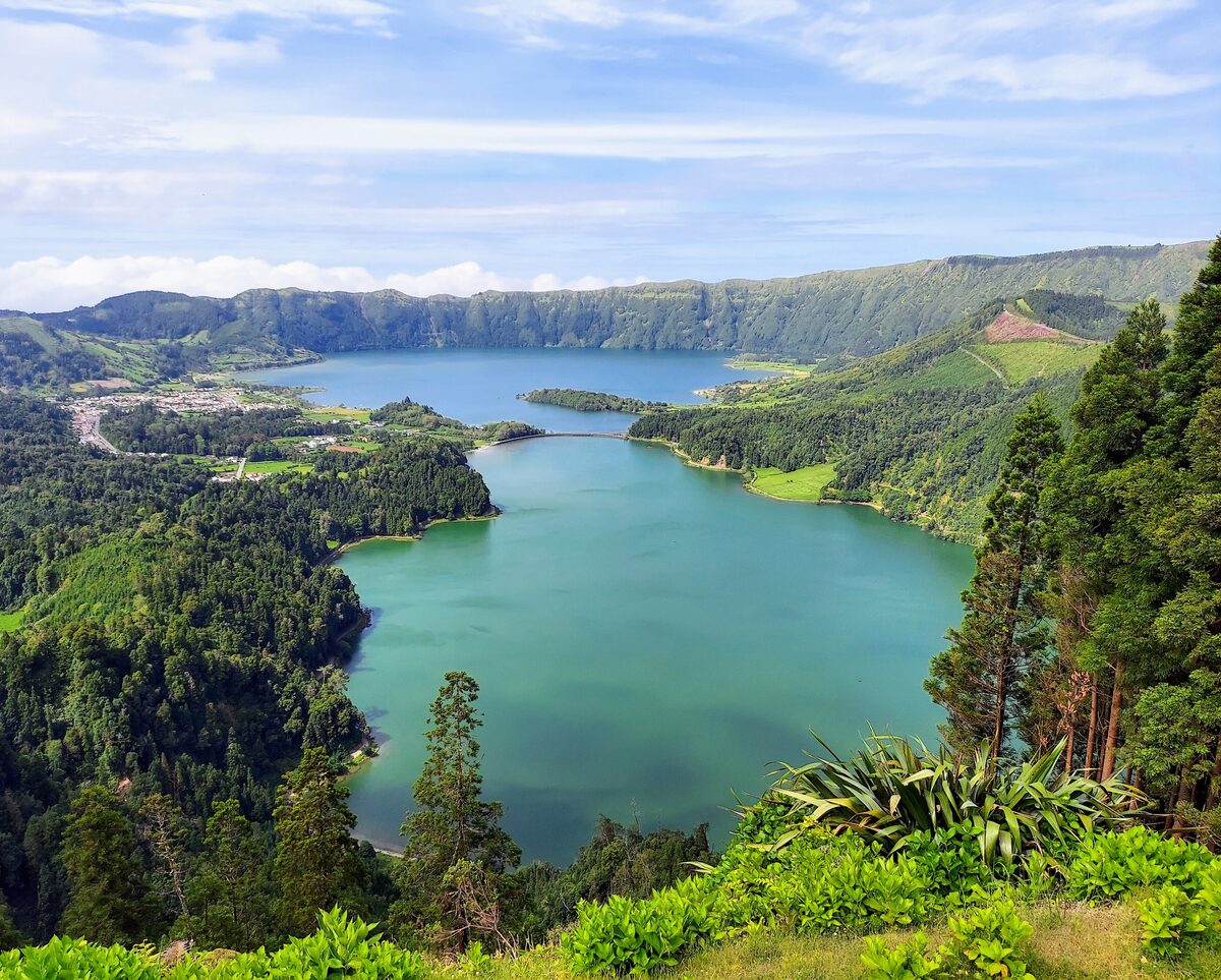 One of the Sete Cidades lakes far below the Vista do Rei viewpoint, with the village on its shore and forested slopes around