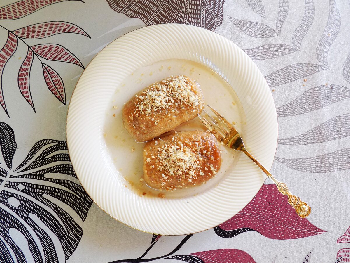 Two syrup-soaked hurmašice sprinkled with ground nuts on a white plate, here a Tutin version of the dish