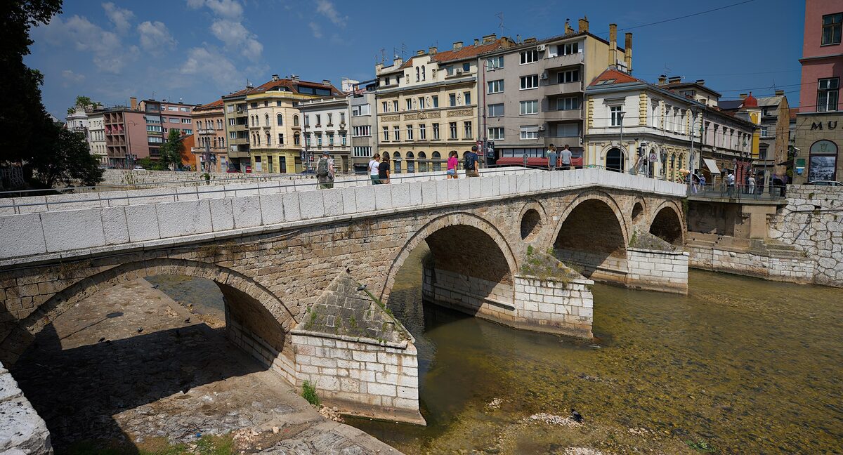 The Latin Bridge over the Miljacka, its stone arches and the old-town facades on the far bank behind it