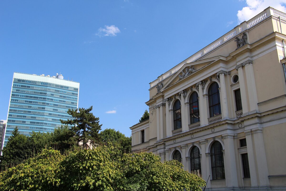 The neoclassical National Museum of Bosnia and Herzegovina, a cream facade with tall arched windows under a blue sky