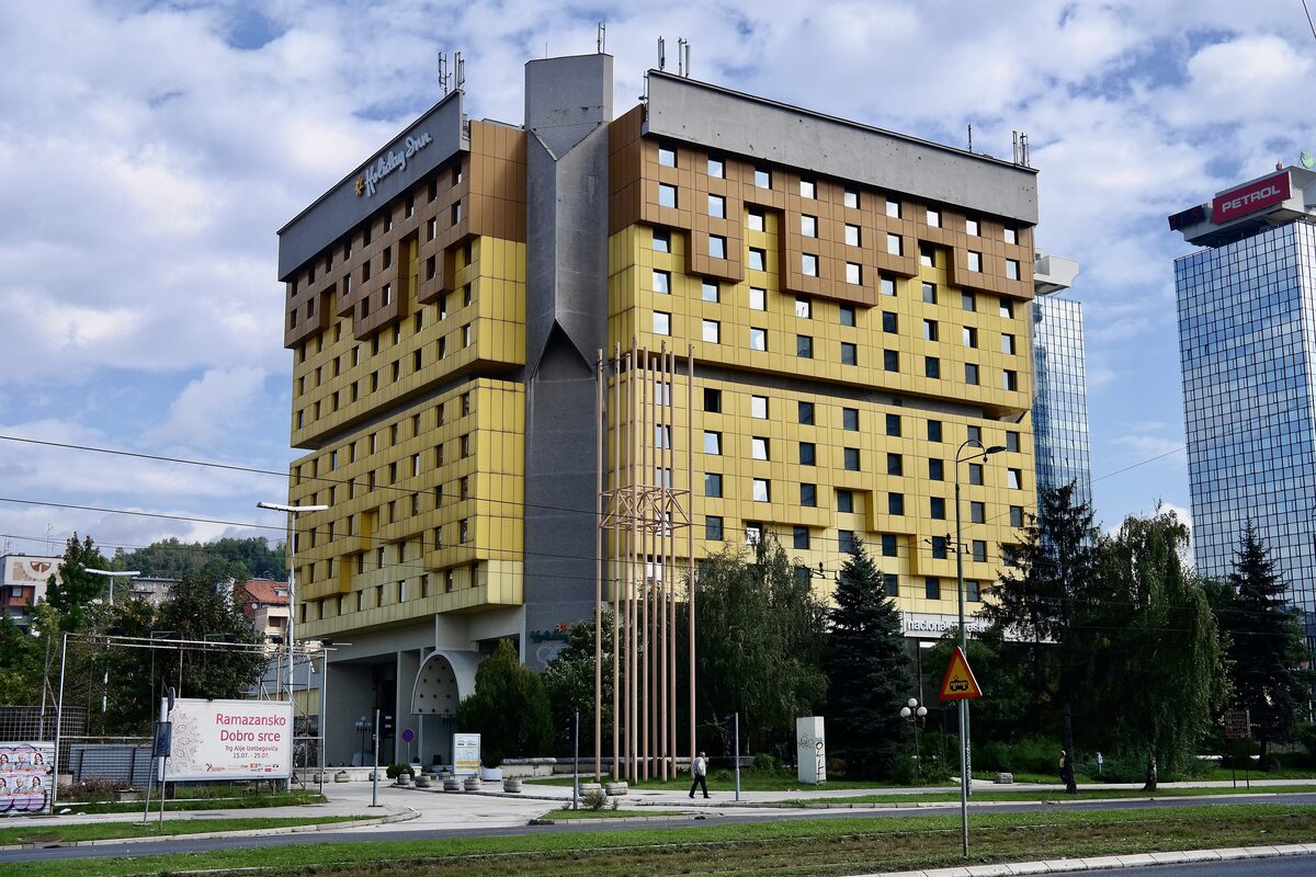 The yellow Holiday Inn tower on Zmaja od Bosne, the avenue known as Sniper Alley, under a blue sky