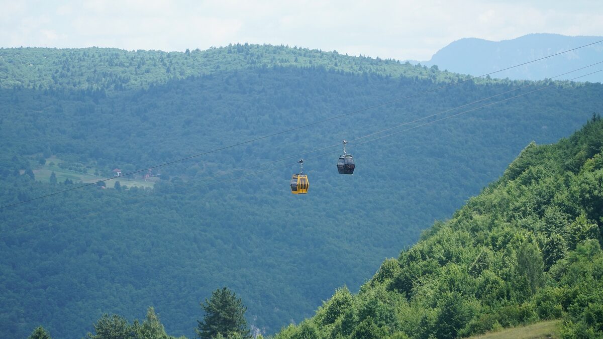 Two cable car cabins crossing the wooded slopes of Trebević above Sarajevo