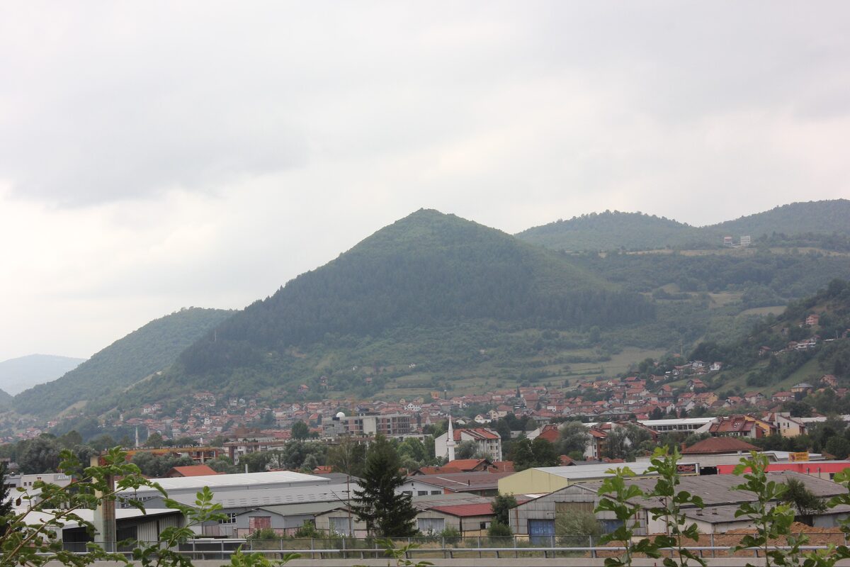 Visoko under the wooded Visočica hill, the one claimed to be a pyramid, with red roofs and a factory zone in the valley below