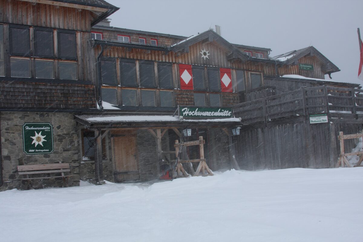 The Hochwurzenhütte mountain hut in snow, with its name board on the wooden wall