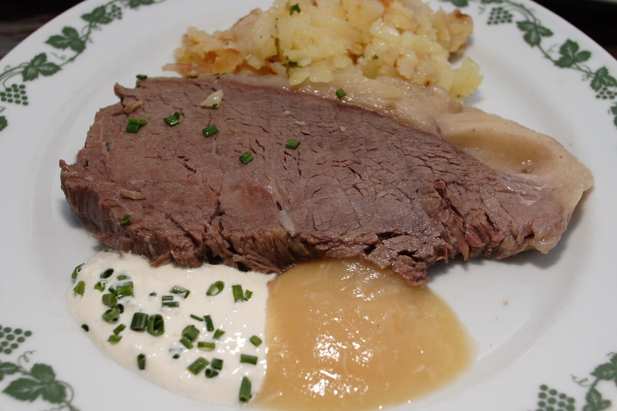 Sliced boiled beef with chive sauce, apple horseradish and potatoes on a plate