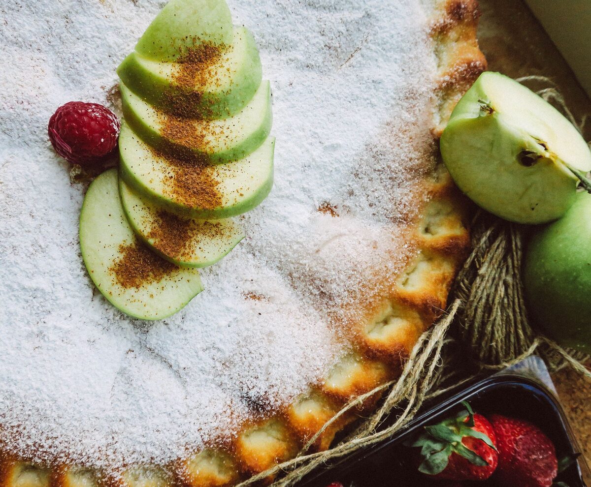 Sugar-dusted apple pie topped with fanned green apple slices