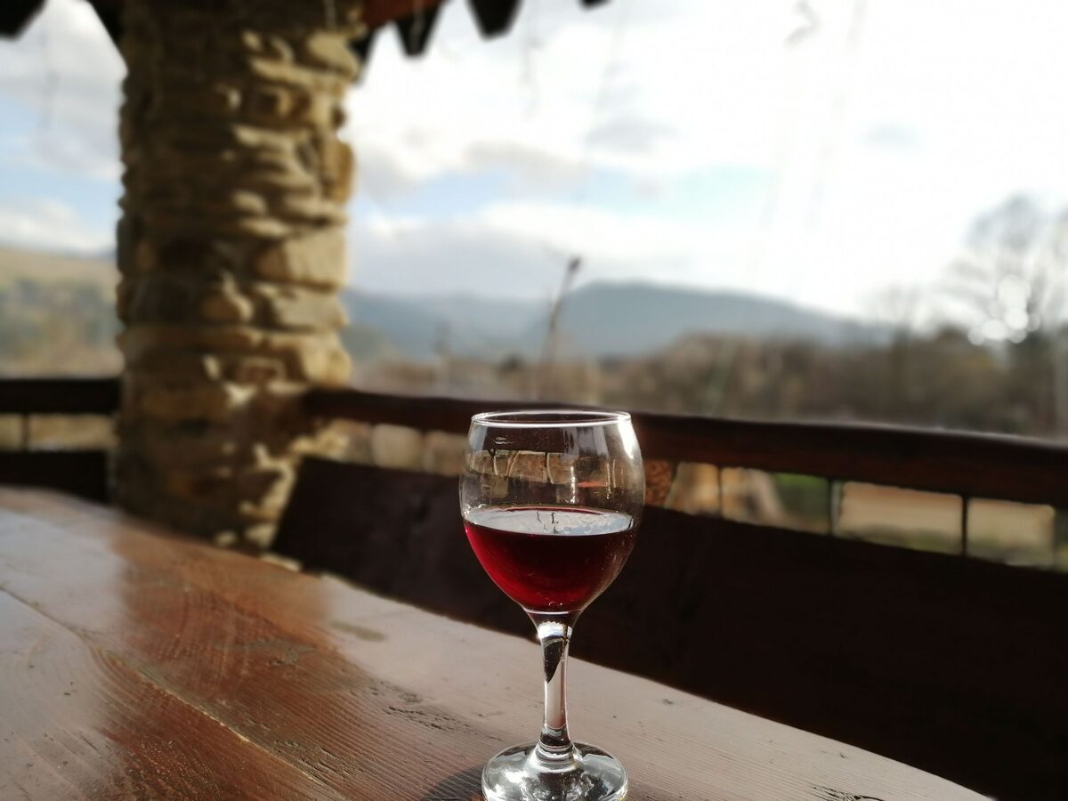 A glass of red wine on a terrace table above hills